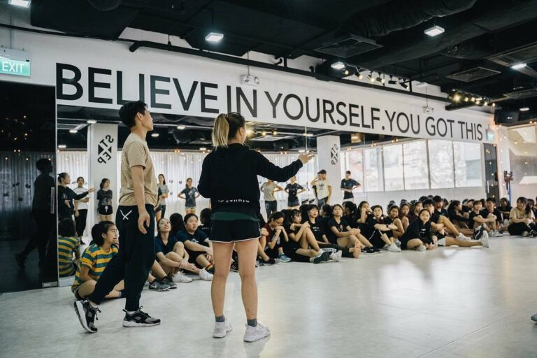 Modern dance studio in Singapore with instructor leading a large group dance class in a spacious training hall.