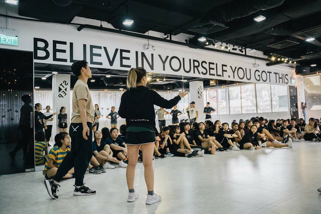 Modern dance studio in Singapore with instructor leading a large group dance class in a spacious training hall.
