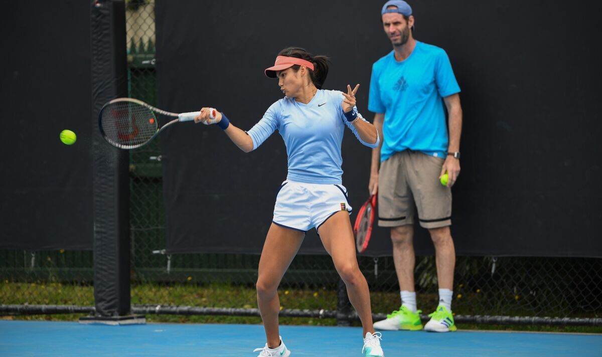 Best Tennis Coaches Singapore professional tennis coach teaching a beginner player proper forehand technique on an outdoor tennis court.