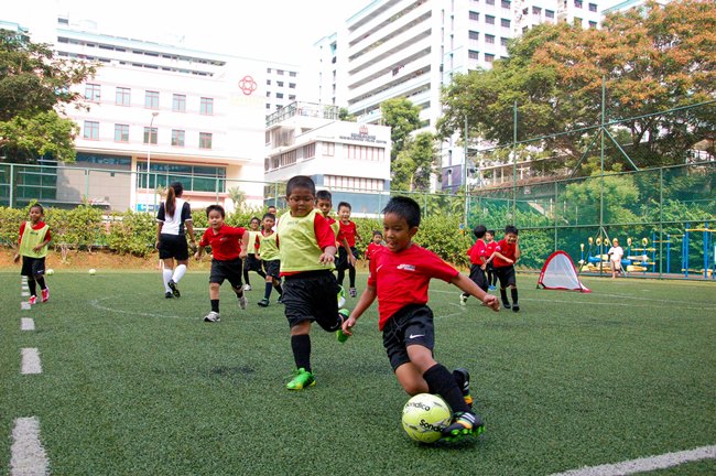 Best Football Academies Singapore Children training at a football academy in Singapore during a youth soccer practice session.