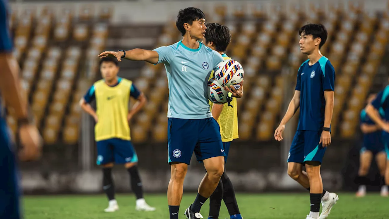 Football coach instructing young players during a soccer academy training session in Singapore.