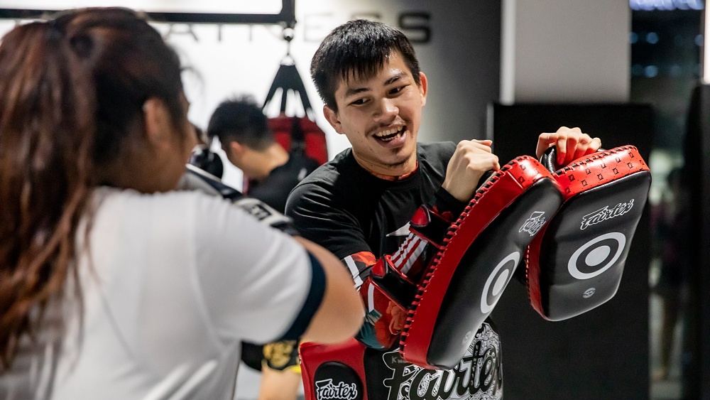 Martial arts training session in Singapore with instructor holding focus pads during combat sports practice.