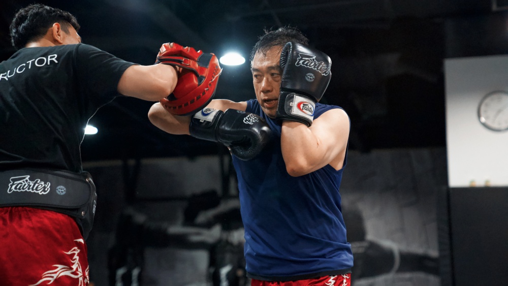 Martial arts students practicing boxing and striking drills with protective equipment in a training gym.