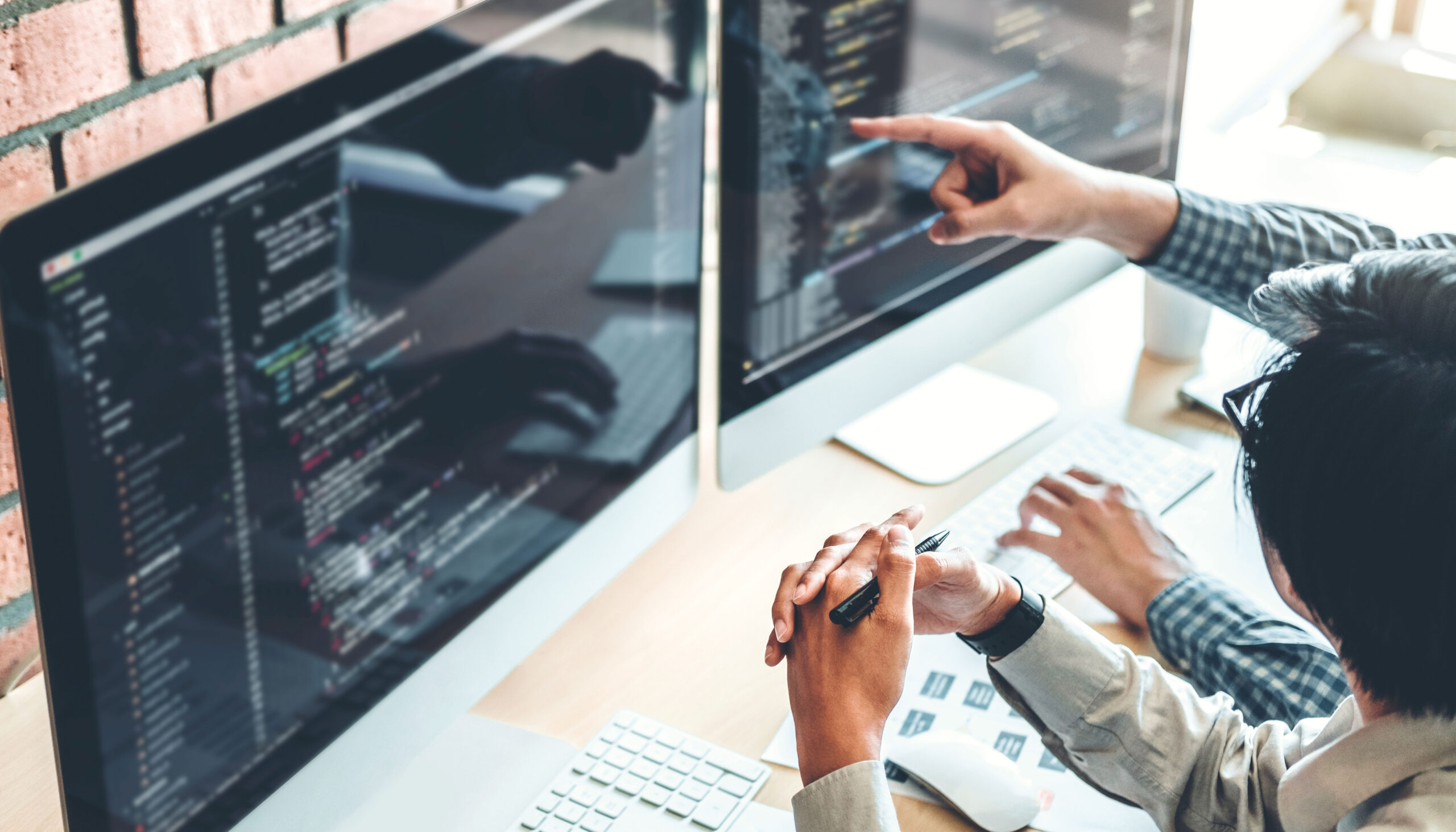 Best Software Companies Singapore Programmers writing and reviewing software code in a development office