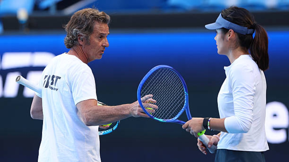 Experienced tennis coach discussing technique with a student during a professional tennis training session in Singapore.