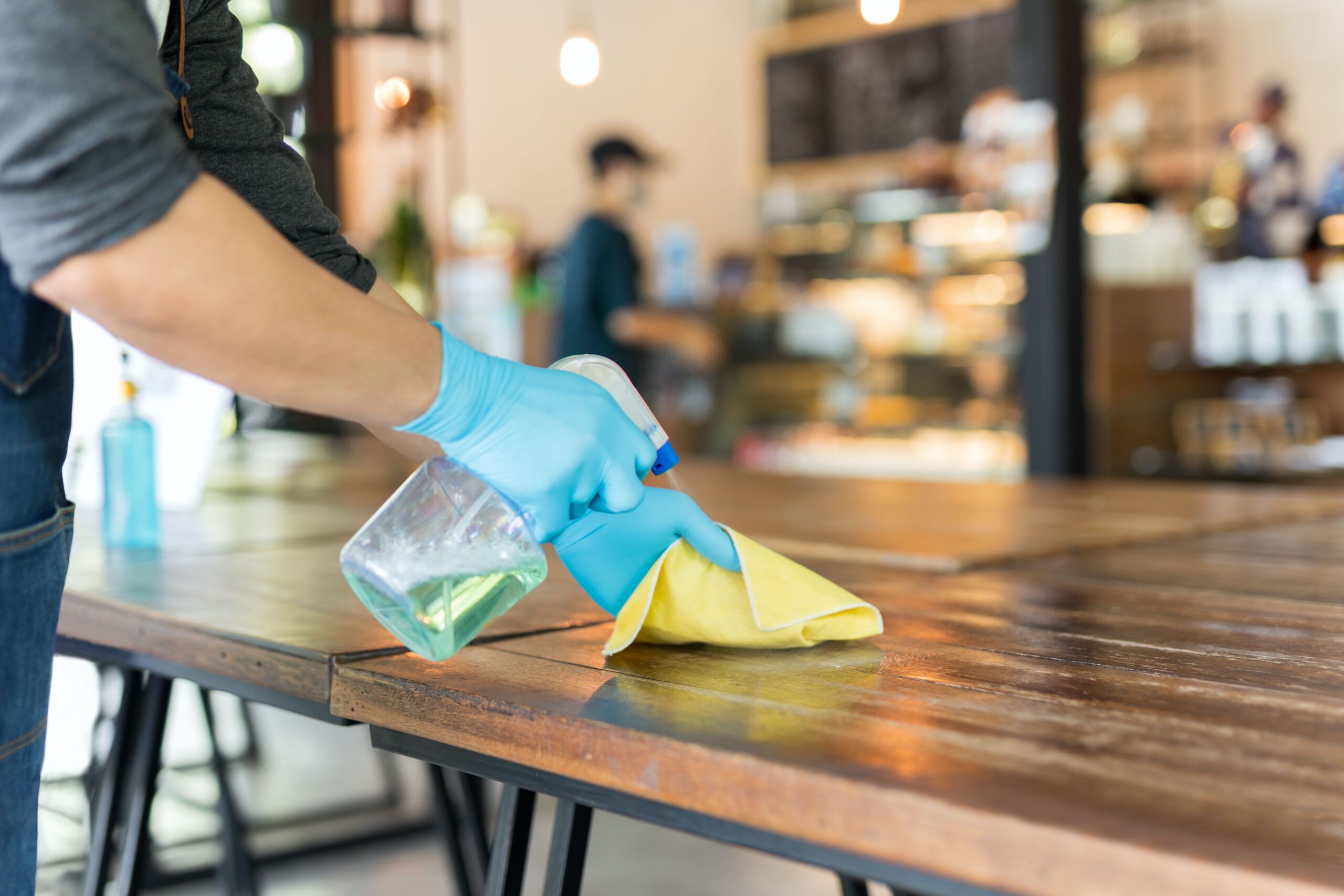 Commercial cleaning staff disinfecting office desk and workspace